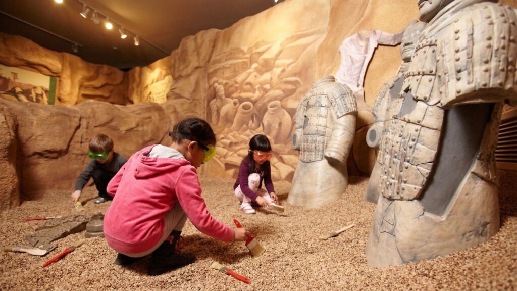 An image of three children interacting at a museum exhibit.
